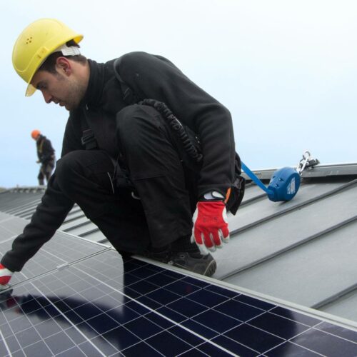 Worker using rail system for working at height to cleaning solar panel